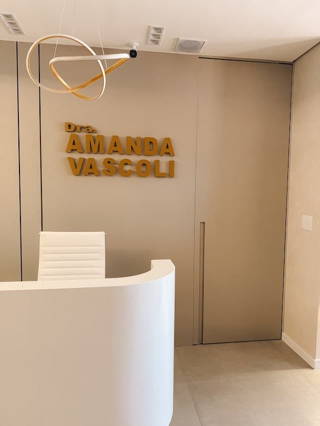 Recepção da clínica, com o nome da Dra. Amanda Vascoli em letras douradas na parede
